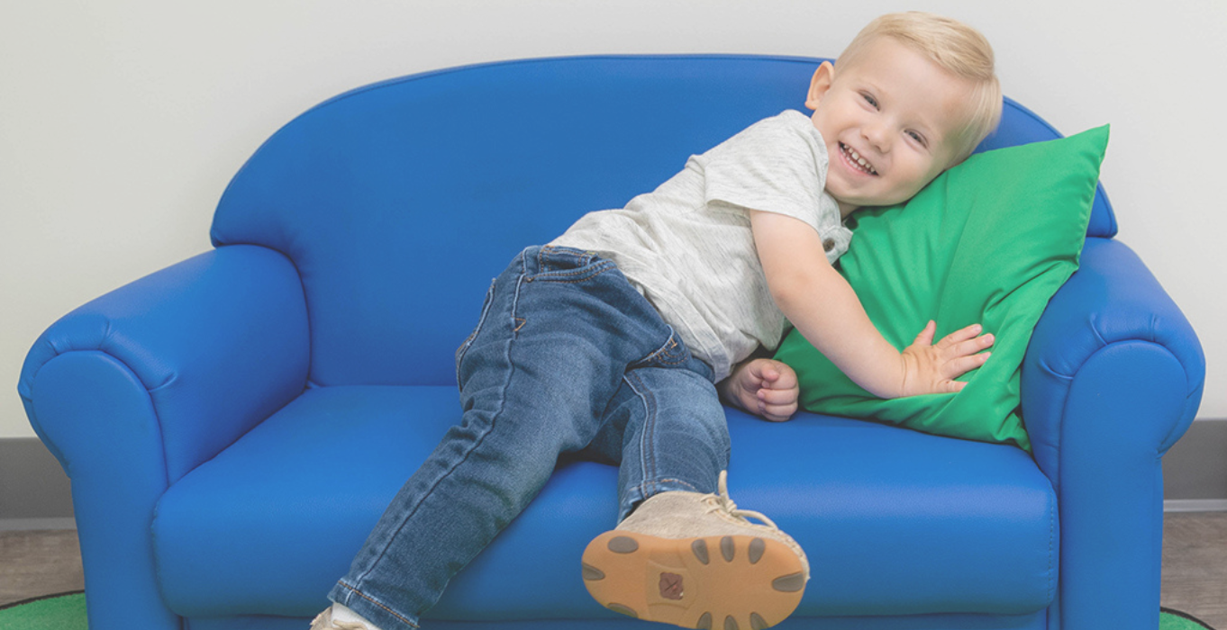 Preschool boy sitting comfortably on a child-size blue couch