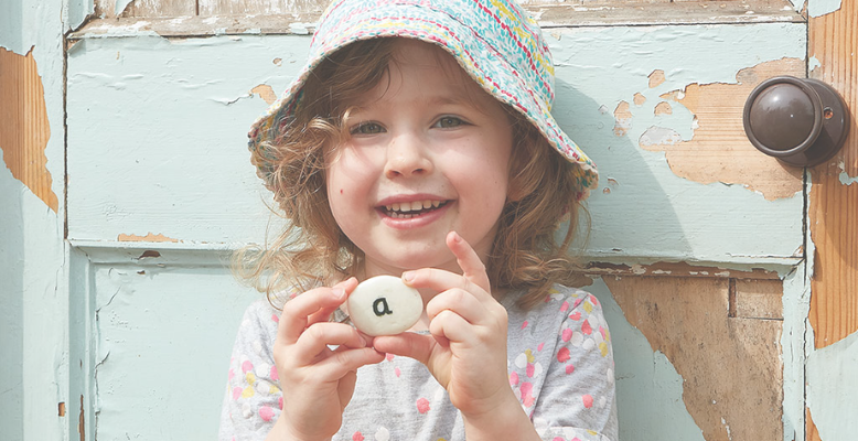 Happy girl holding an alphabet pebble